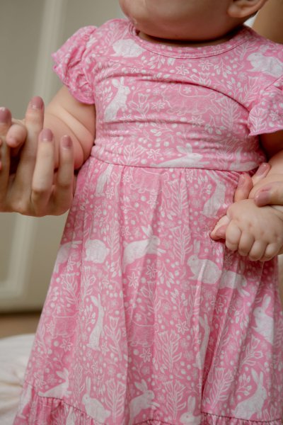 A playful dress with flutter sleeves and skirt in House of Holly's new Rabbits Rendezvous print, featuring hand-drawn rabbit designs in a charming garden scene. Perfect for family gatherings or playdates, this adorable dress is sure to make your little one stand out. Don't miss out on this meaningful and stylish addition to your child's wardrobe.